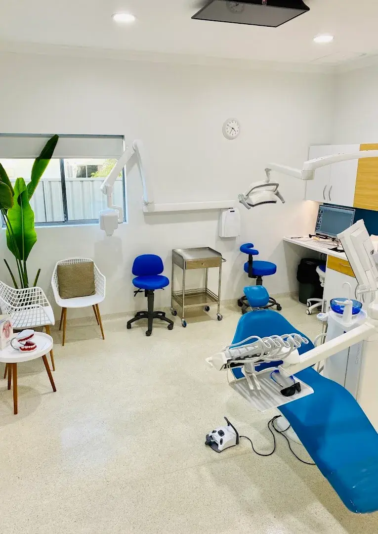 A treatment room at North Beach Dental, with a blue dental chair and a seat by the window